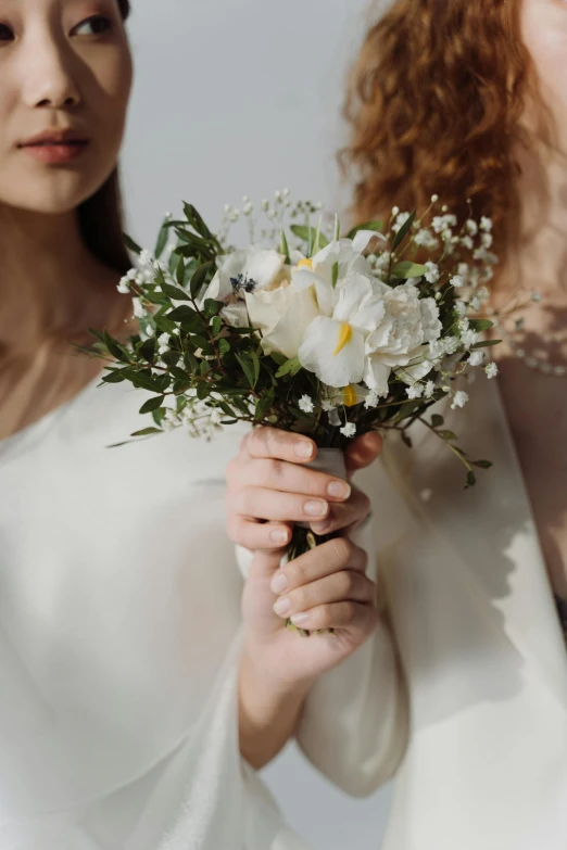 the woman is holding her bouquet with the white flowers in hand