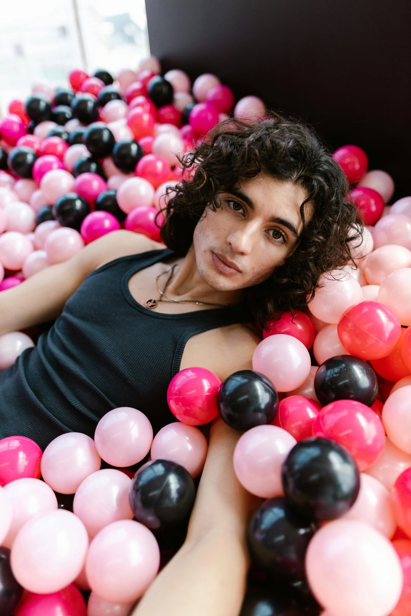 a woman sitting in a pool of pink and black balloons