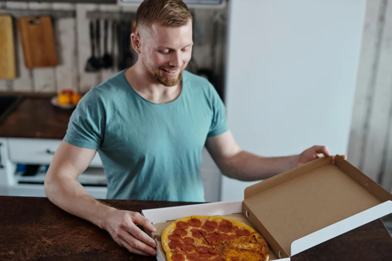 the man is holding a pizza in his hand