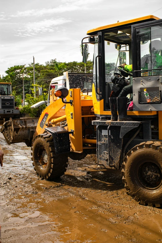 a construction vehicle sitting on the side of a mud road