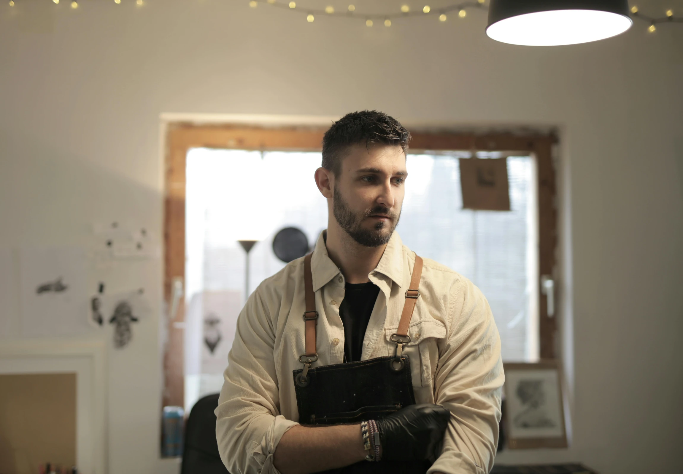 a man in a black apron is holding a book and looking into the camera