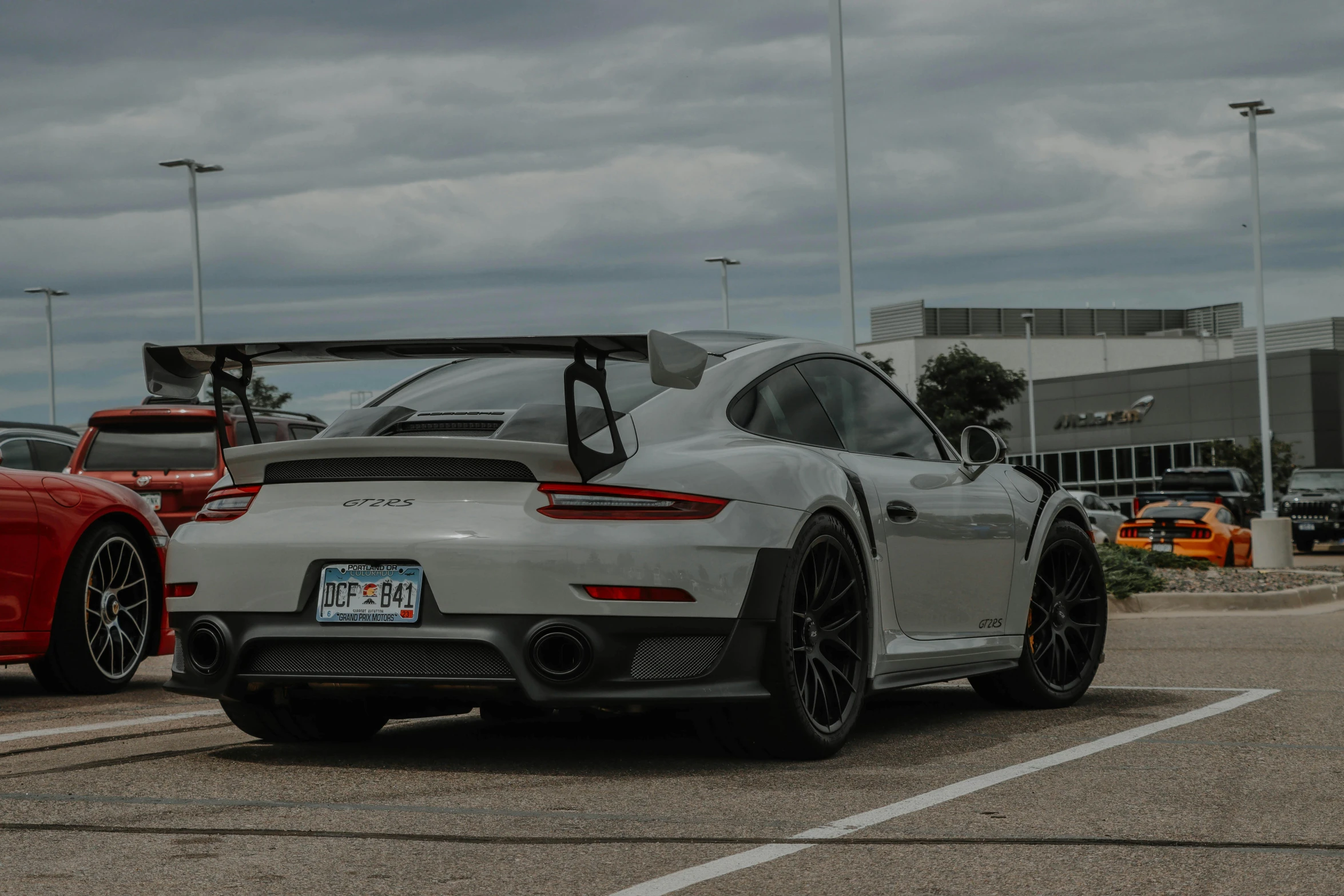 a large grey sports car and two others parked in a parking lot