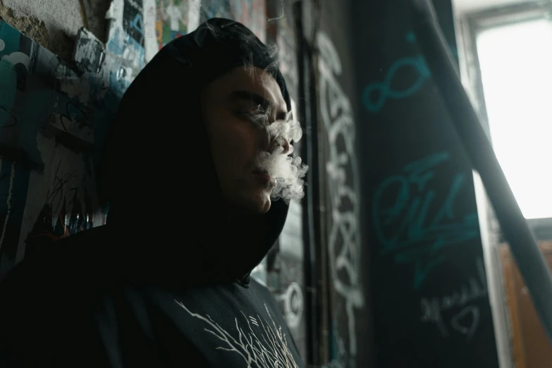 a man wearing a hoodie smoking a cigarette