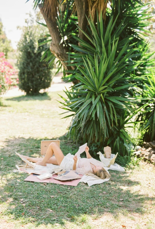 a woman is laying on her stomach on a blanket outside