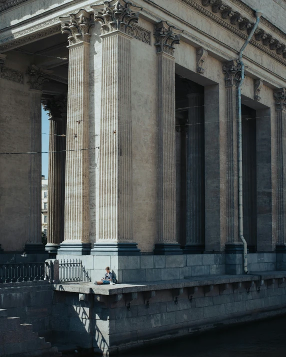 a tall building with pillars near a body of water