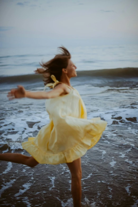 a  in a yellow dress is running on the beach