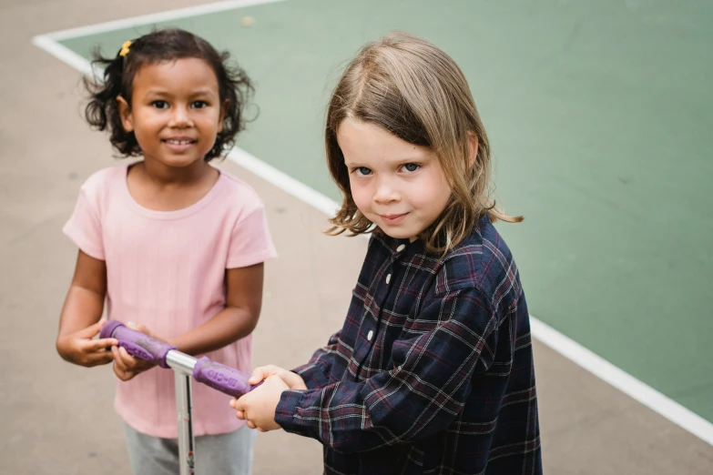 two girls stand on a tennis court with their rackets