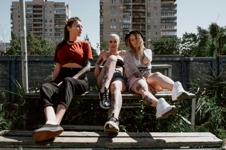 three women sitting on a bench in front of a brick building