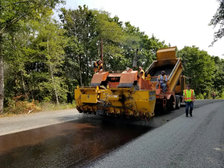 two men wearing construction gear walk near a big truck