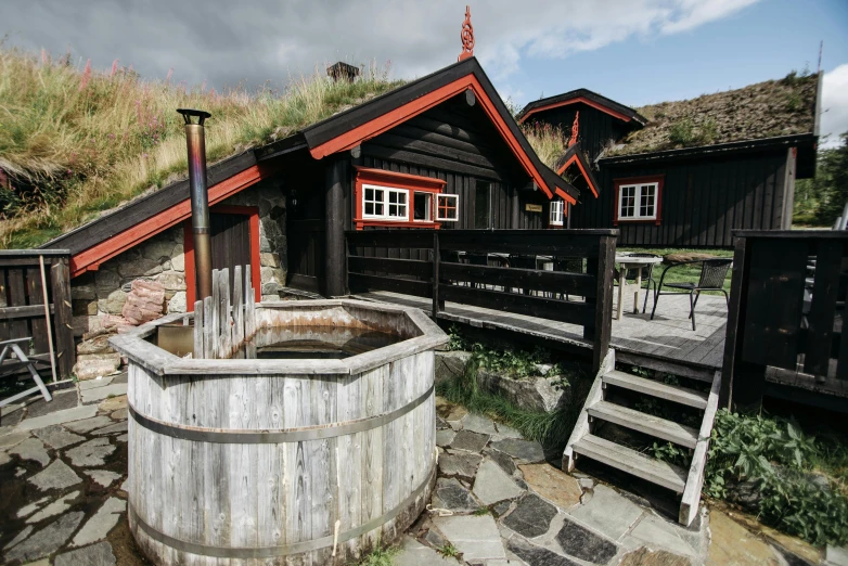 wooden buildings with a  spring, in the foreground a mountain and picnic table on the far side