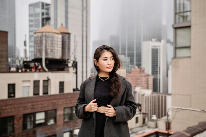 a woman with long hair posing for a picture in front of tall buildings