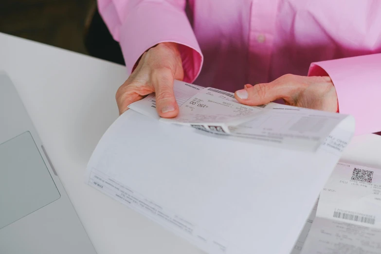 two hands are holding receipts over a desk