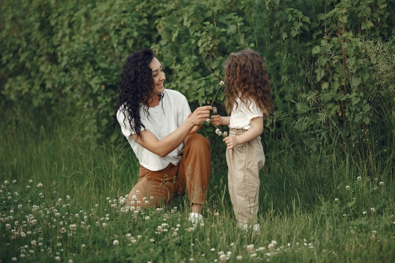 two little girls are in the middle of a grassy field with a man sitting on the ground