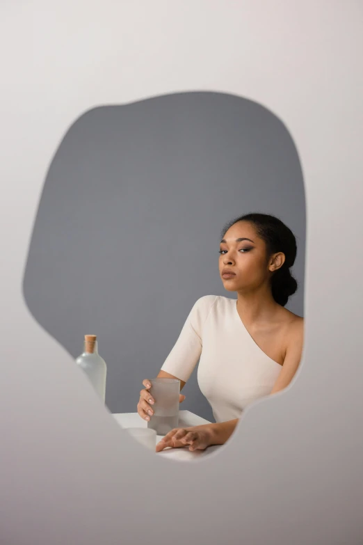 a woman holding up a bottle of alcohol, from the side