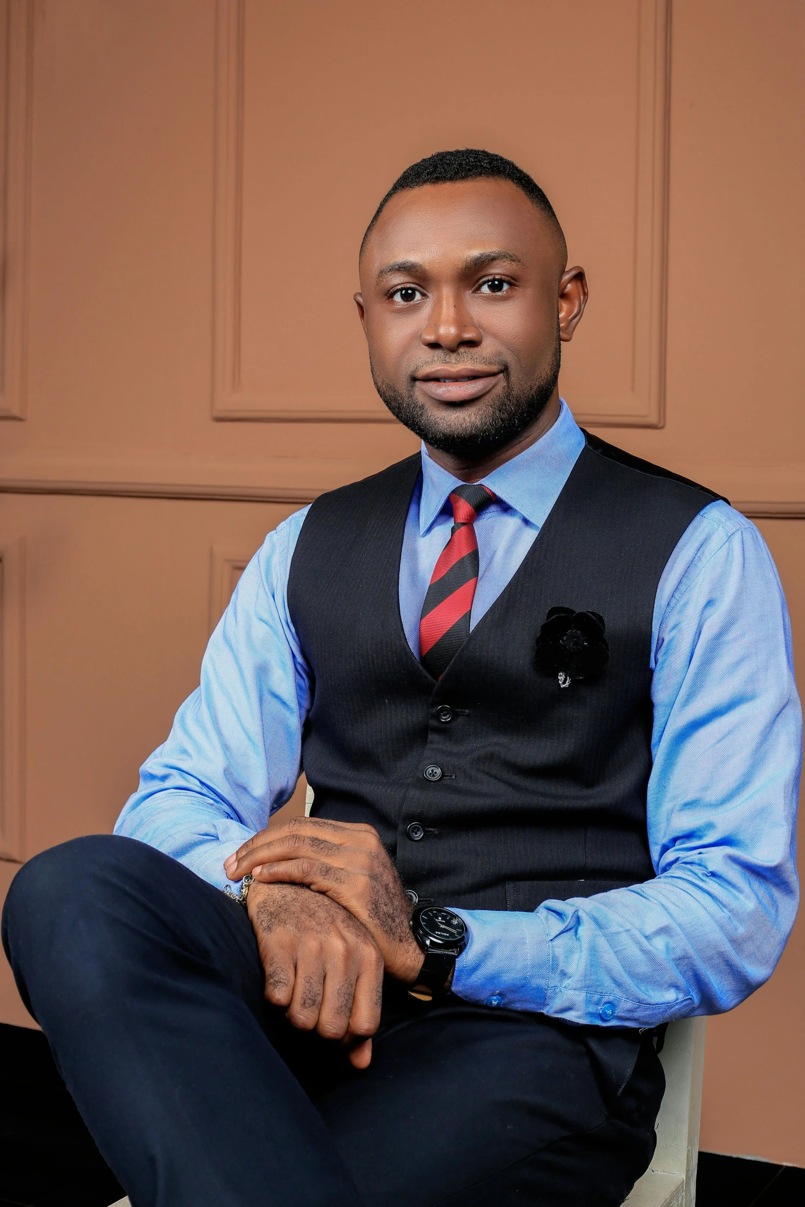 a man sitting on a chair in front of a wall wearing a blue shirt and tie