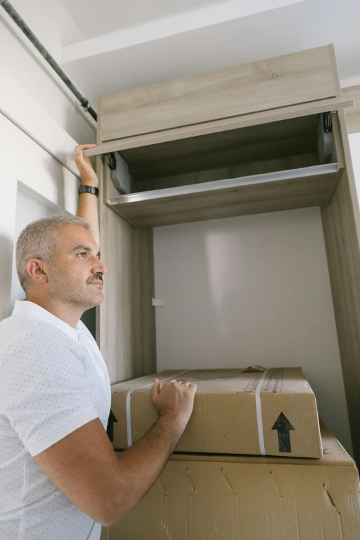 a man in white shirt looking at cardboard boxes