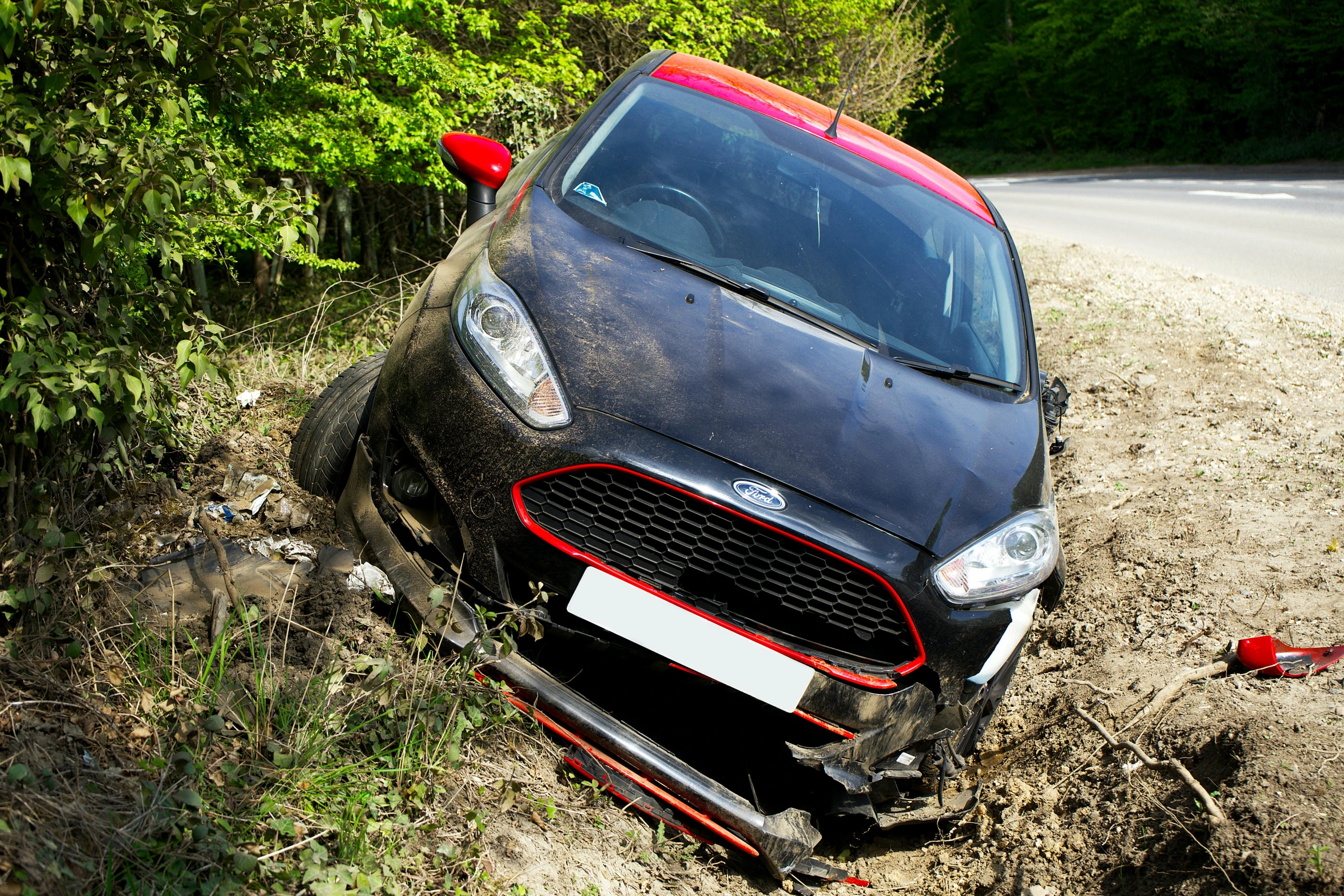 a black car with red accents on its hood parked on the side of a road