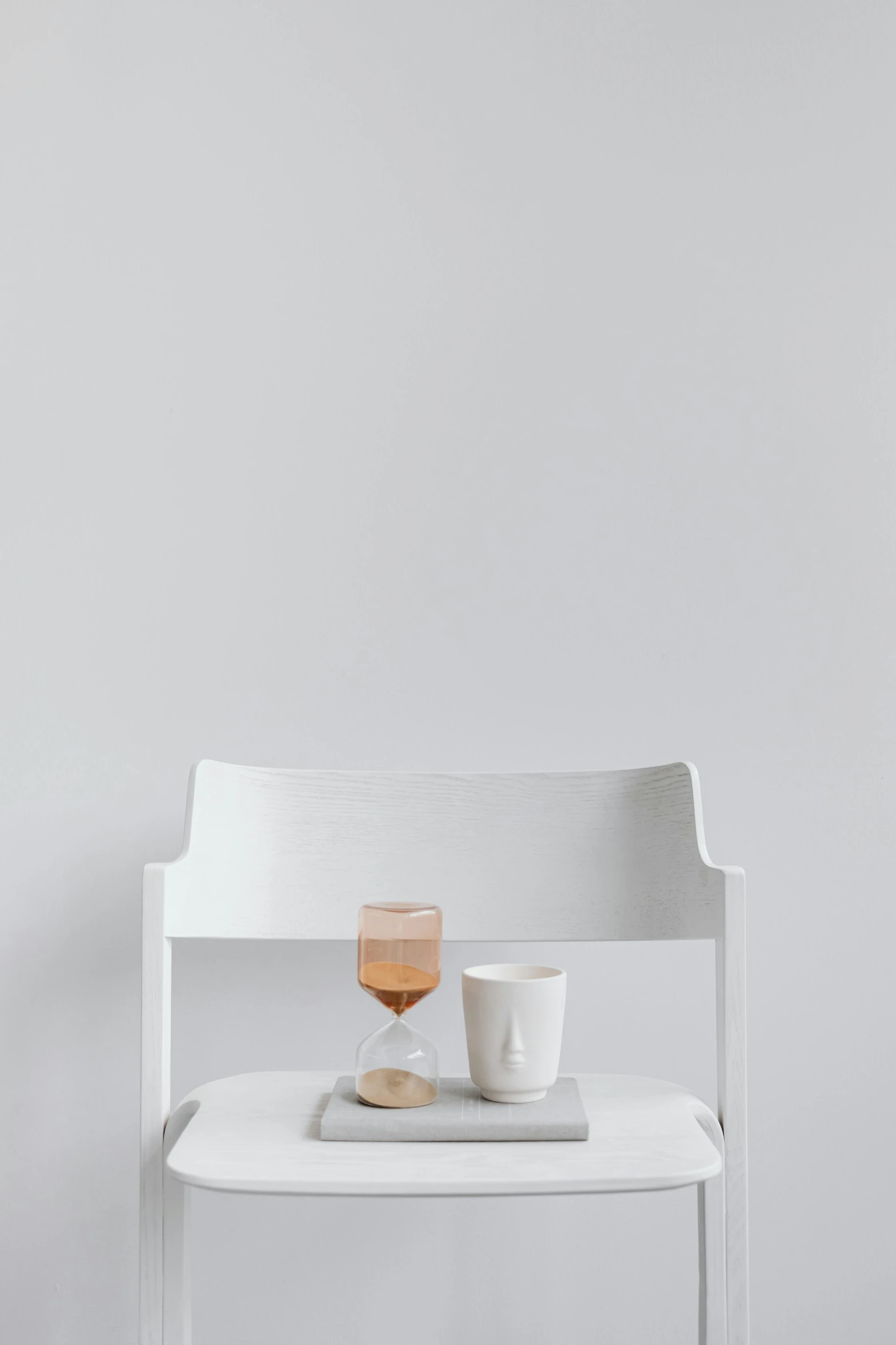 a white bench with two cups and a book on it