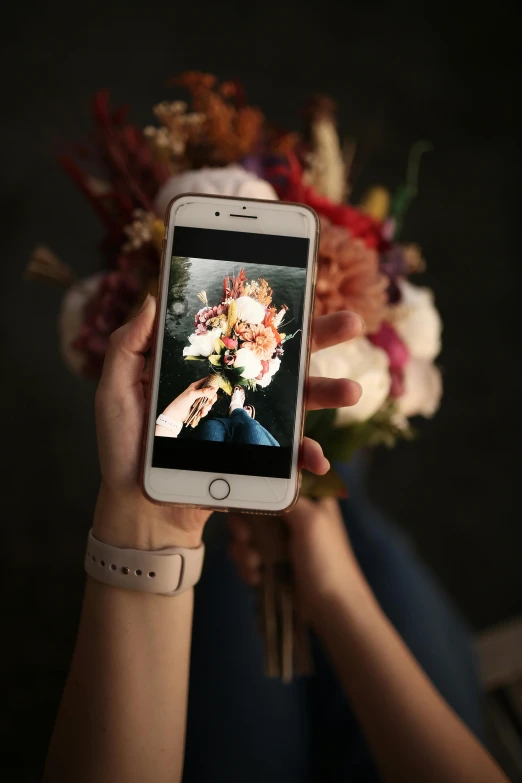 a girl holding a phone with a floral arrangement on the screen