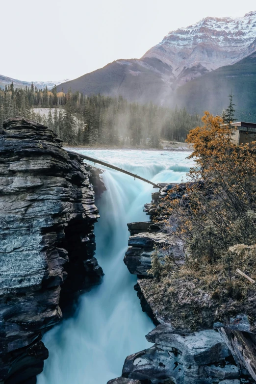 a waterfall flowing into a river surrounded by mountains