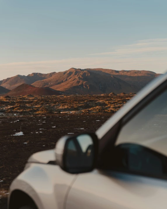 a car in the desert is looking out towards a distant mountain