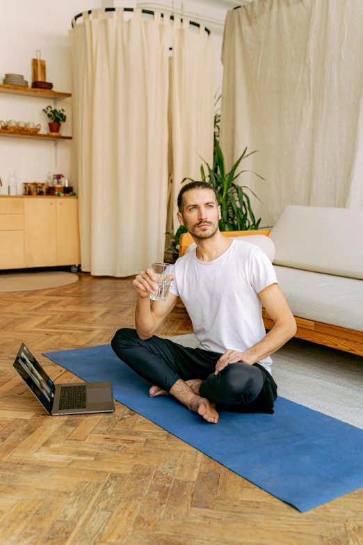 a man sitting in a lotus position drinking water