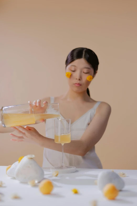 a woman pours drinks from a vase with orange fruit on the table