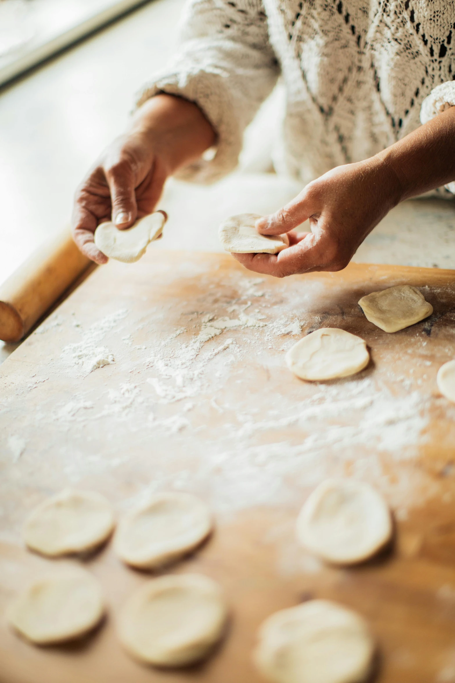 a person that is kneading soing out on a table