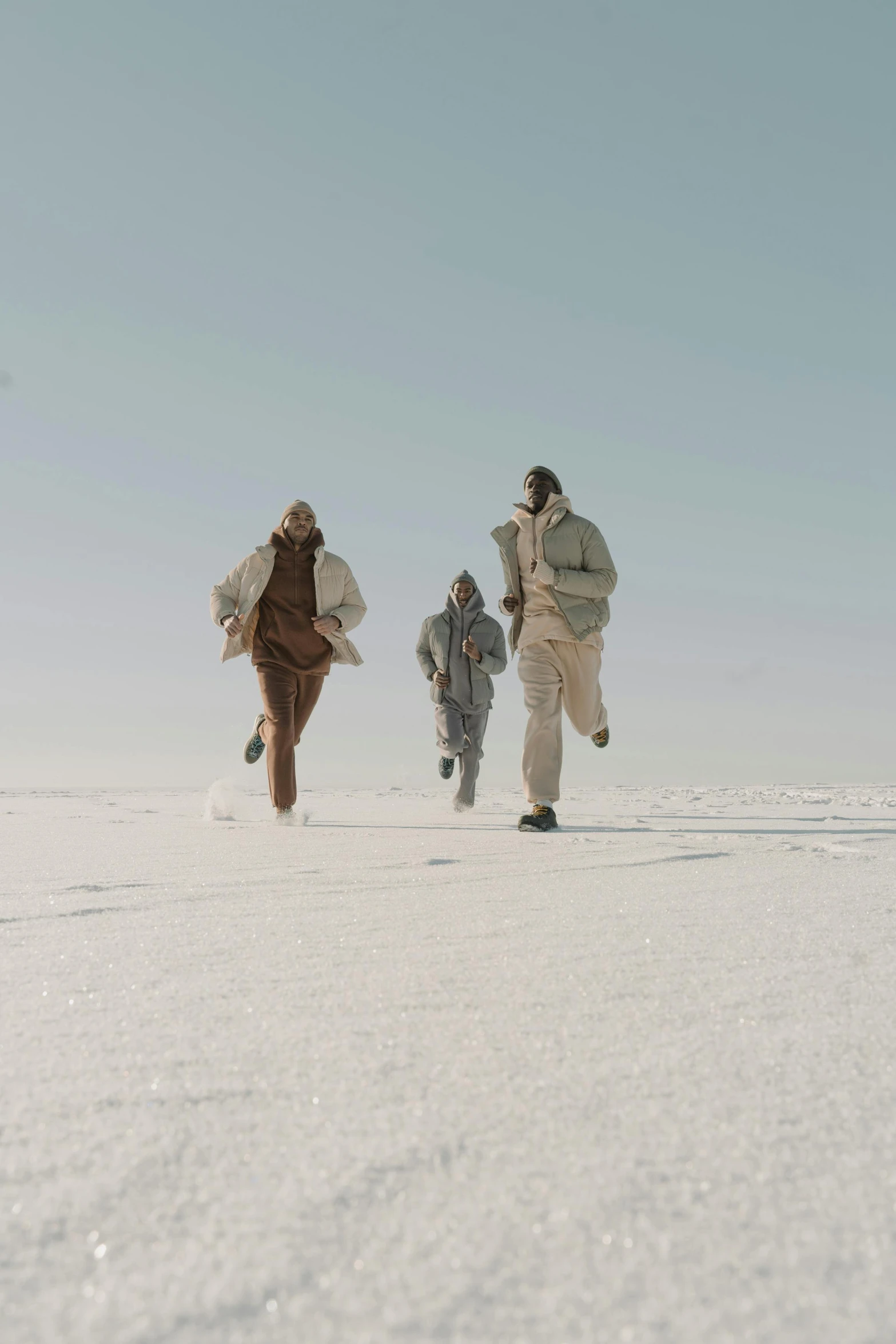 three people walking in the snow in coats