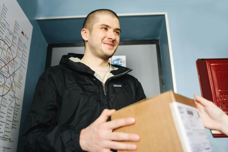 a young man with a cardboard box is smiling