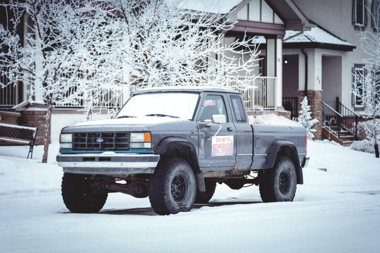 an older ford truck in the snow parked