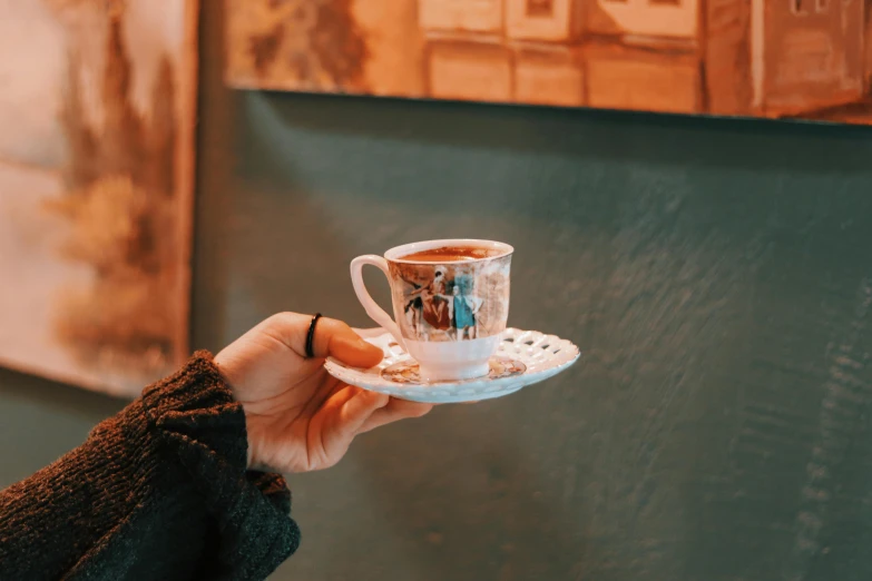 a person holds a teacup with two people