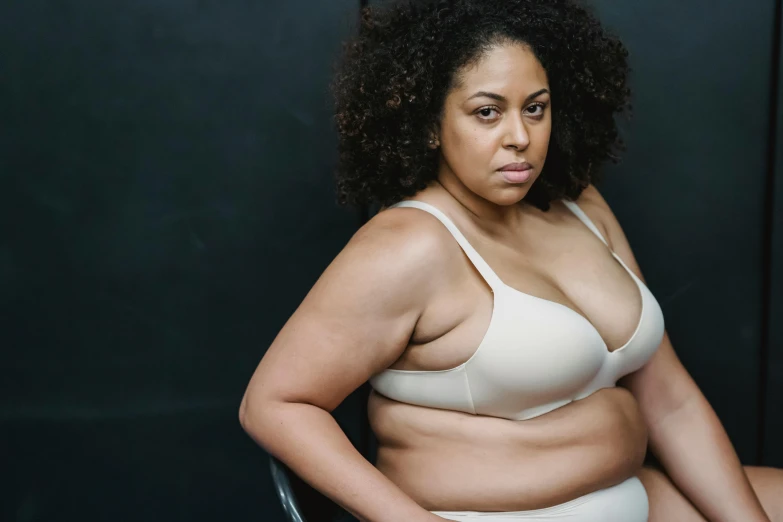 a woman is sitting on a chair with an overweight body