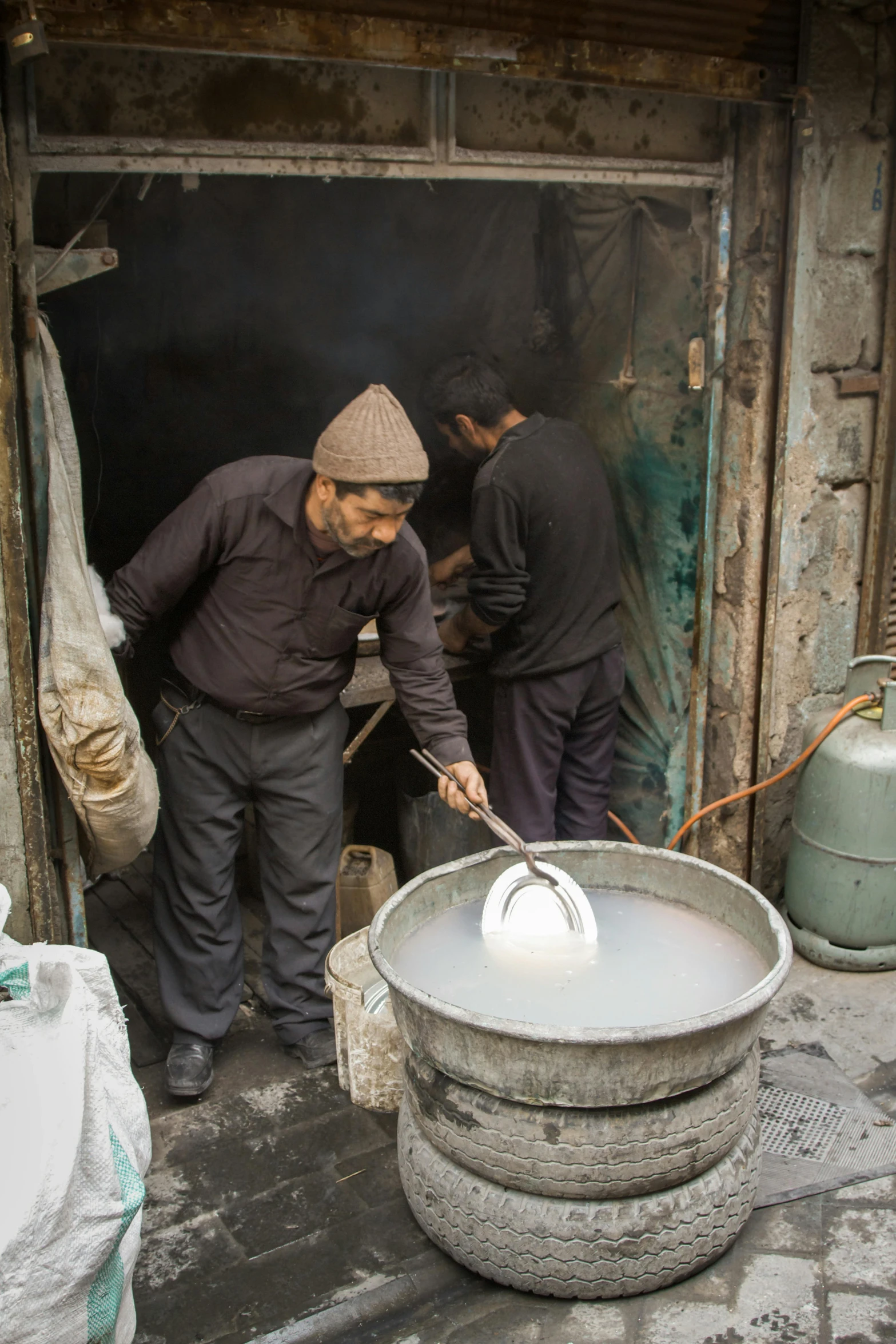 two men are washing their dishes inside a stone - walled area