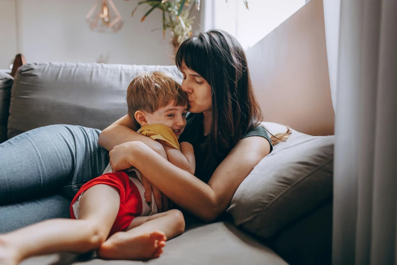 a mother and her son cuddle together on a couch