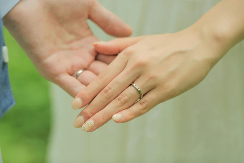 an engaged couple holding hands with the man's wedding band