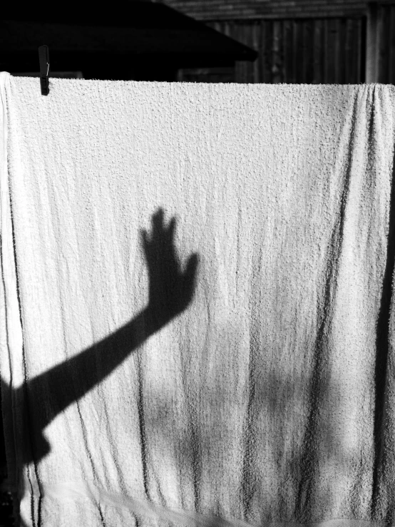 shadows cast on white towels and the shadow of a hand