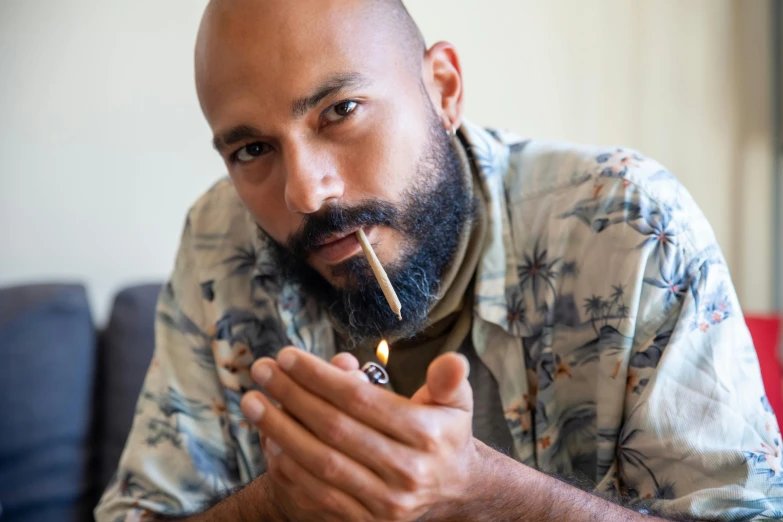 a man is sitting on a couch holding a lighter in his mouth