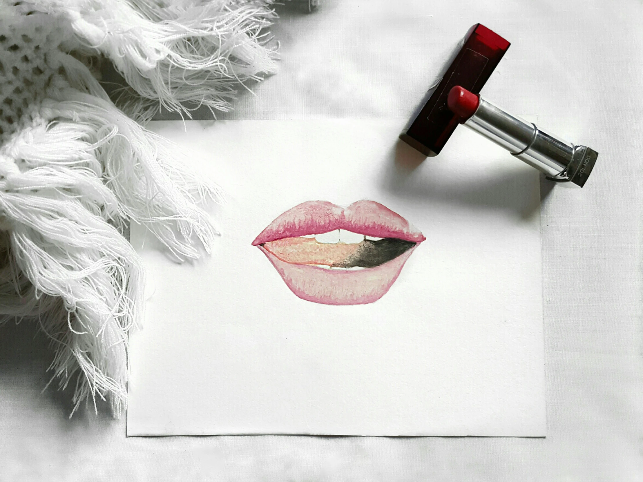 lipstick on a piece of paper next to a lipstick bottle