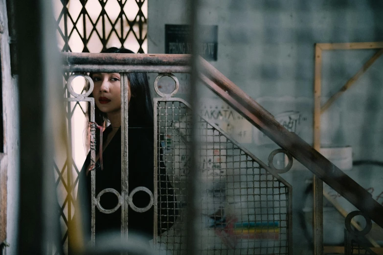 a girl peeking from behind bars in an enclosure