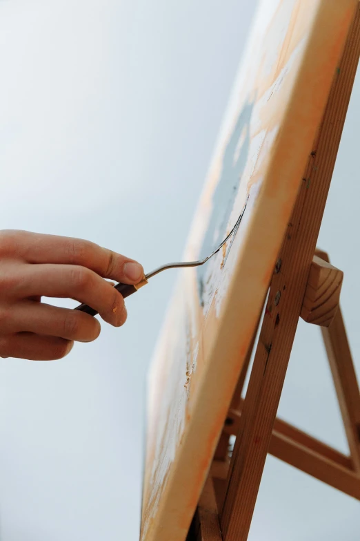 a hand is painting on a canvas with a knife
