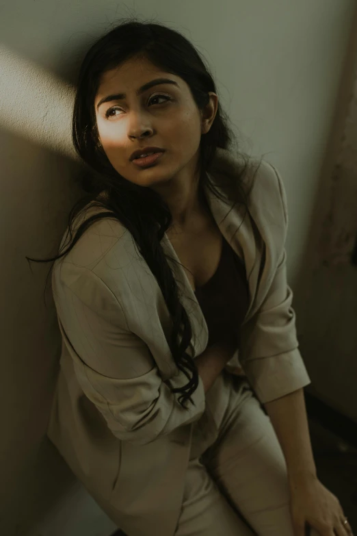 a woman sitting against a wall and looking up