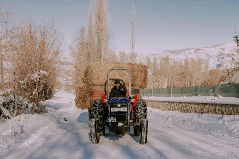 man riding on back of a tractor full of hay