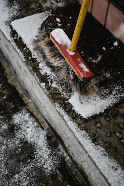 a broom on top of snow near a red building