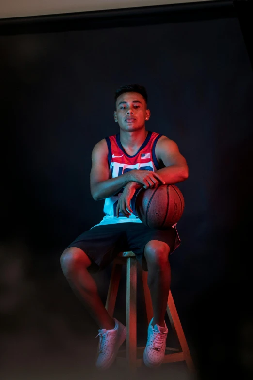 an athlete is sitting on a stool in a darkened po