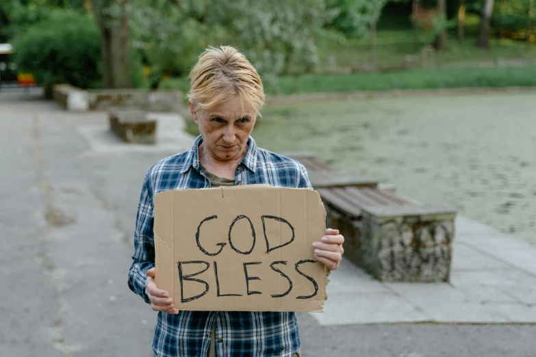 a man holding up a cardboard sign that says god bless