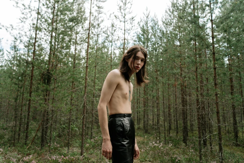 a shirtless man standing in a forest