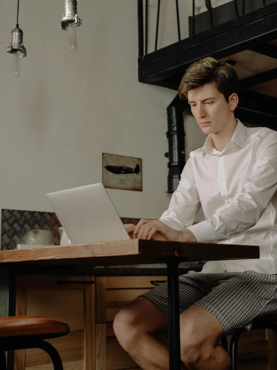 a man wearing a shirt working on a laptop