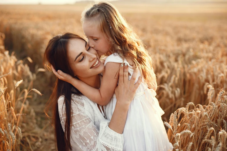 a mother and daughter playing in a wheat field