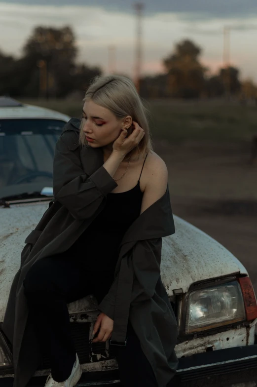 woman leaning on a vehicle outside with her hands on her head